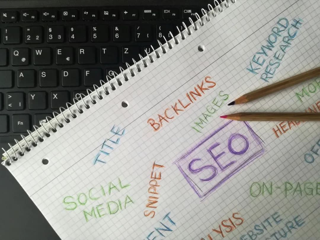 A notebook on a keyboard with hand-written SEO terms such as backlinks and keyword research